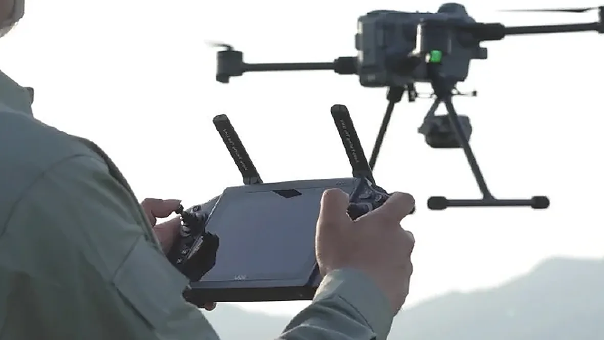 Operator holding a ground control station while adjusting a drone fitted with a micro gimbal, installed weight must be weighed item by item